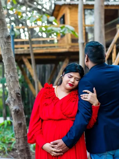 A tender moment in a unique setting with a treehouse in the background. The embrace from behind is a classic pose that conveys a sense of protection and love.