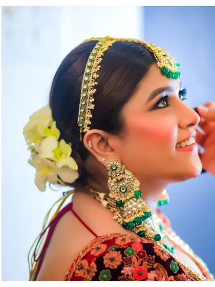 A close-up of the bride during her getting-ready process. The fresh flowers in her hair and her happy expression capture a moment of joyful anticipation.