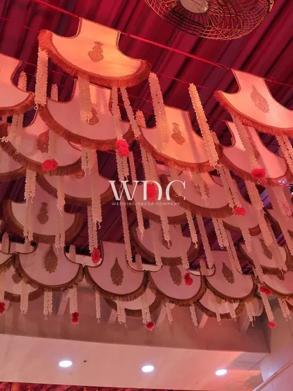 Another beautiful ceiling detail, with hanging decorative panels and strings of white flowers, all under a rich red drape.