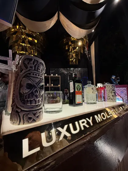 A close-up of our tiki-themed bar, featuring a skull-faced tiki mug and a selection of premium spirits on our branded 'Luxury Molecular Bar' counter.