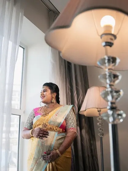 A smiling portrait of the mother-to-be, looking radiant and happy by the window during her Seemantha celebration.