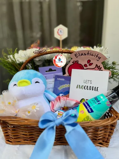 This cute double-sided basket hamper includes a soft penguin toy, Miniso products, a fun "Let's Avocuddle" card, and other skincare goodies, all tied with a lovely blue bow.