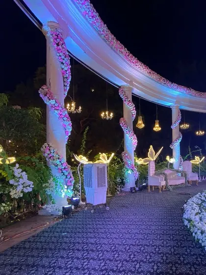 A closer look at the details of the reception stage. We wrapped the pillars in white florals and hung mini chandeliers to add a touch of opulence and romance to the decor.