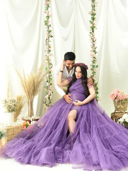 A romantic couple's portrait on our floral swing set. The mom-to-be's vibrant purple gown cascades beautifully, filling the scene with color and texture.