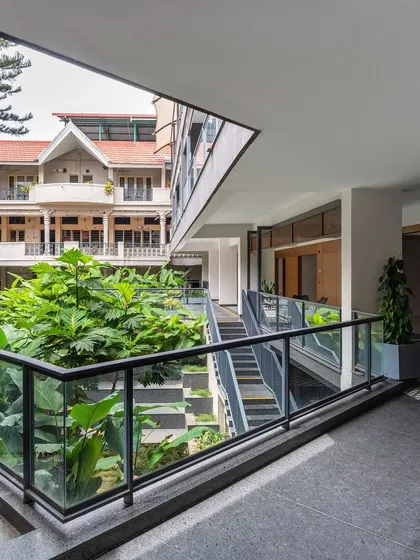 The design of the Koramangala Club Annexe incorporates open corridors and courtyards that forge new relationships with the landscape and existing buildings. This view shows a new staircase descending into a green courtyard, enhancing circulation and connectivity.