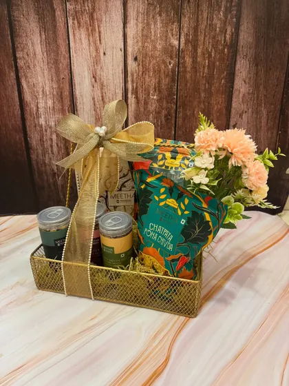 A more compact version of our desi snack hamper for Rakhi. It's filled with delicious 'chatpata poha chivda' and other treats, finished with an elegant bow and a small floral touch.
