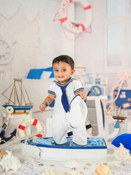 Ahoy, little sailor! This nautical-themed setup with a boat, lifebuoy, and sailor outfit is perfect for an adventurous little one.