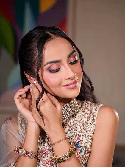 A close-up of a soft, dewy makeup look. The eyes have a beautiful wash of pink and brown, and the skin is absolutely glowing, perfect for a Mehendi or engagement.