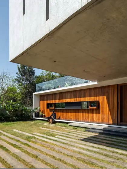 A dramatic view of the Long House, where a massive concrete cantilever provides shade and architectural presence over a timber-clad lower level.