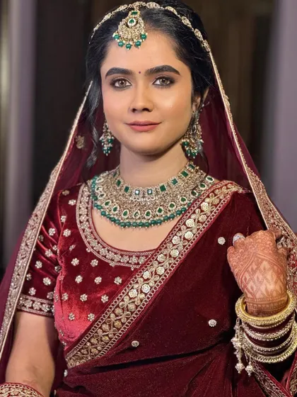 A close-up portrait of the bride. Her eyes are defined with a soft smoke, and the skin is kept luminous to balance the heavy emerald jewelry.