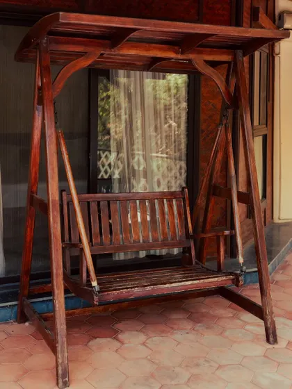 The simple charm of a wooden porch swing, perfect for enjoying the gentle breeze and quiet moments.