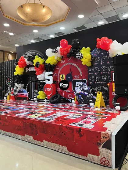A wider view of the Ferrari party stage, showing the balloon arch with the birthday boy's name, 'Shivaay', and a lit-up number '5' to mark the special milestone.