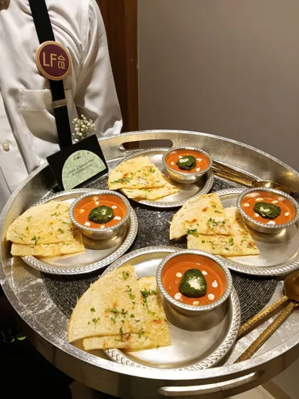 A server presenting individual portions of soup and naan. This thoughtful presentation allows guests to enjoy a comforting classic in a convenient, single-serving format.