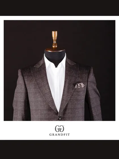 A close-up of the brown plaid jacket, styled simply with a white shirt to let the rich pattern and expert tailoring take center stage.