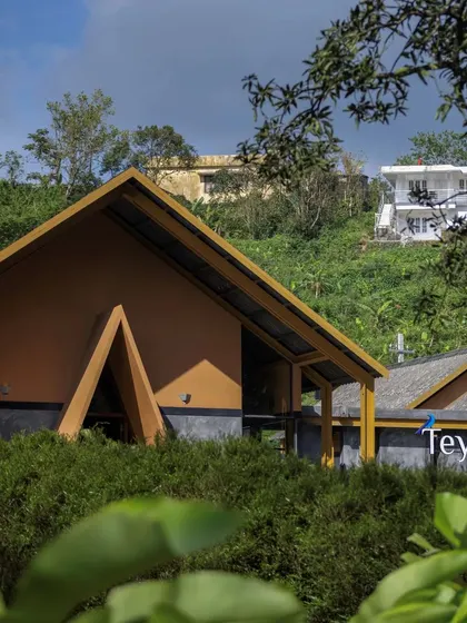 The cafe nestled in the lush green hills of Idukki, Kerala. The design uses earthy tones and natural forms to blend with the tea estate landscape, creating a structure that feels like it belongs to the place.