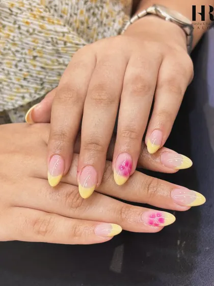 A sunny and cheerful design. This look features a soft yellow French tip on an almond-shaped nail, with a single, beautifully hand-painted pink flower as an accent.