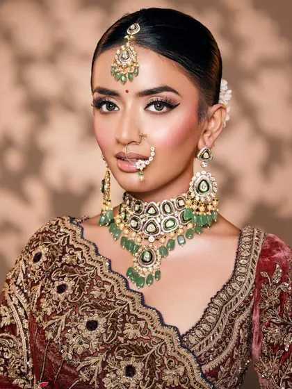 A beautiful portrait with a slight smile, showcasing the complete bridal styling from the maang tikka to the choker.