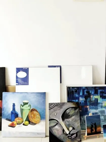 Another view of my studio wall, showcasing a mix of still life, abstract, and spiritual paintings. On the right, you can see my shelf of paints and supplies.