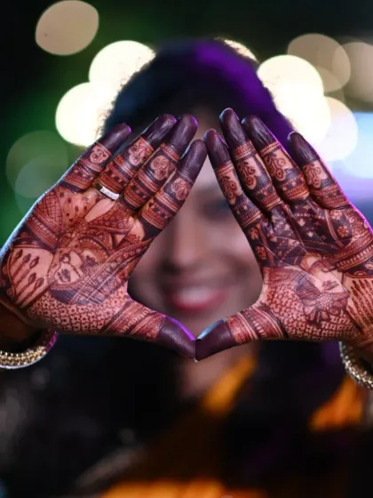 A creative shot of a bride framing her face with her hands. The intricate mehndi and the dark stain create a stunning visual.