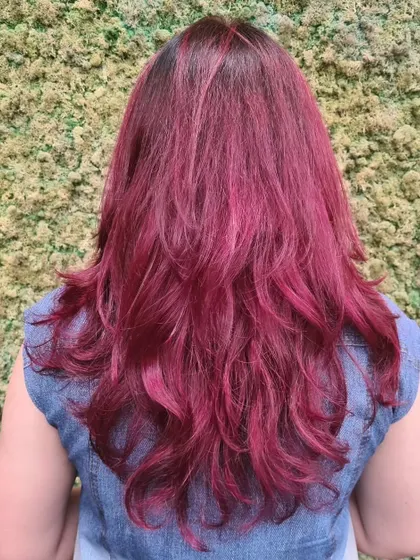 A vibrant, all-over magenta hair color with layers to add movement and show off the bold shade.