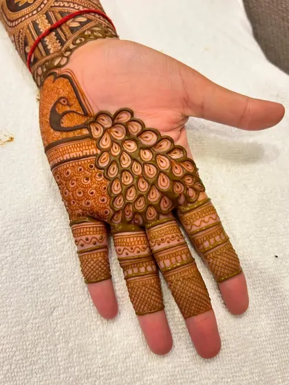 A close-up of a peacock motif where the feathers elegantly cover the fingers. This is a creative way to incorporate a classic element into the design.