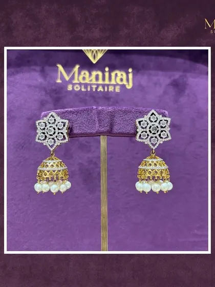 A touch of traditional charm with a modern twist. These exquisite jhumkas feature a star-shaped diamond stud with a classic gold and pearl bell. The intricate craftsmanship makes them truly special.