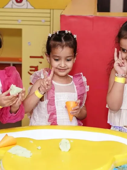 Three girls work together to build something creative at the sand table.