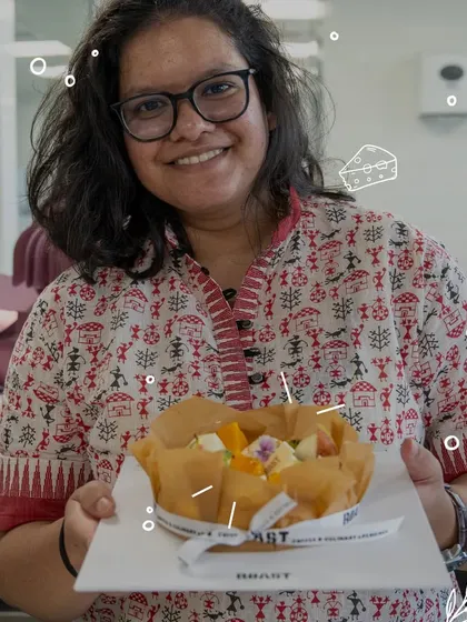 A proud baker shows off her finished fruit-topped cheesecake. The smile says it all; there's immense satisfaction in creating something so beautiful and delicious.