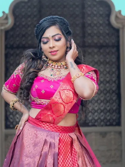A vibrant pink lehenga paired with a matching Kundan and pearl choker set. The matching earrings and maang tikka complete this festive look.