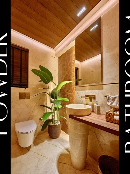 We designed this powder room to create a luxurious experience for guests. The space features a freestanding pedestal sink, warm marble walls, a wood-paneled ceiling, and a large plant to add a touch of nature.