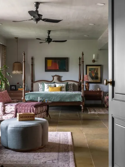 The master bedroom in Dhaka, viewed from the doorway. The room is designed as a complete retreat, with a seating area, beautiful art, and a calm, muted color palette.