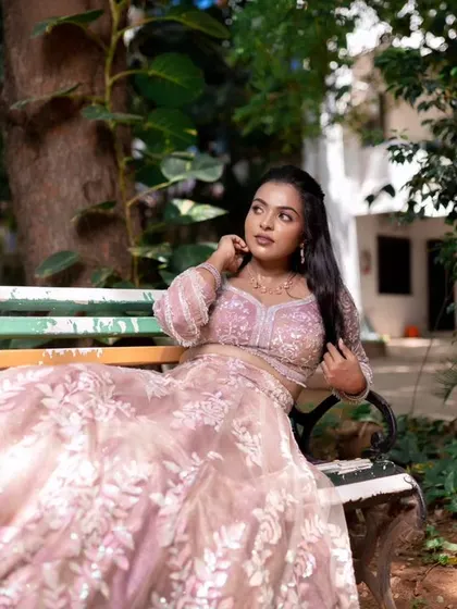 A model posing in a beautiful pink lehenga, showing off a subtle and elegant makeup look.