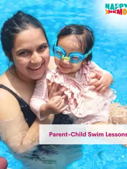 A smiling mom and her little one, who is getting comfortable with swim goggles.