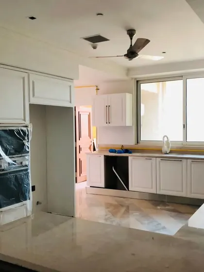 A classic white kitchen under construction, showing the shaker-style cabinets and space for integrated appliances. This image highlights the quality of our custom cabinetry before the final touches.