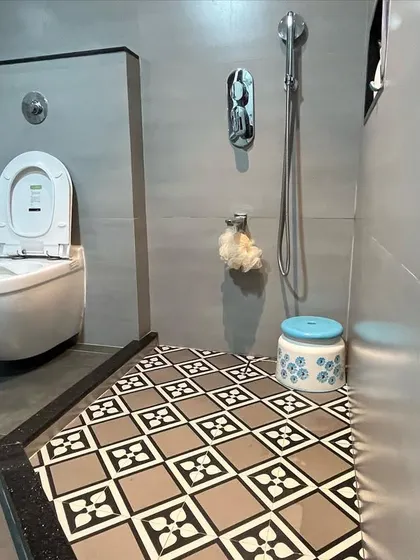 Another view of a modern bathroom, showing the separation of wet and dry areas using a floor-level partition and distinct tile patterns.