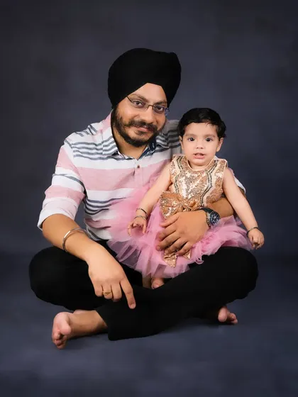A father and his little girl, dressed in a sparkling pink dress, pose for a classic portrait. A beautiful memory of a dad and his daughter.
