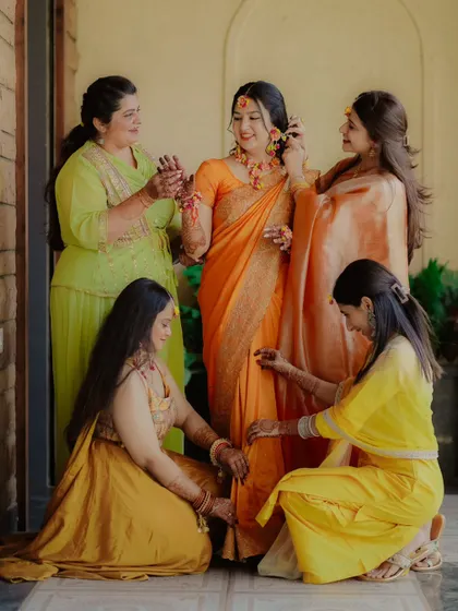 A heartwarming moment as the bride is surrounded by her bridesmaids and family, who help her get ready for the Haldi ceremony.