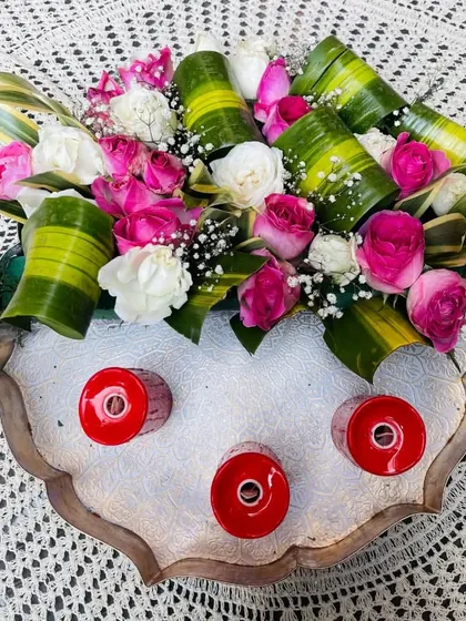 This flower urli bowl, filled with a beautiful arrangement of pink and white roses, elevates any space with its timeless beauty. It's a perfect centerpiece for a special occasion.