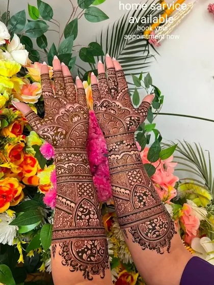 A lovely shot of a full bridal mehndi set against a backdrop of flowers. The design is a classic mix of Indian floral and paisley patterns.