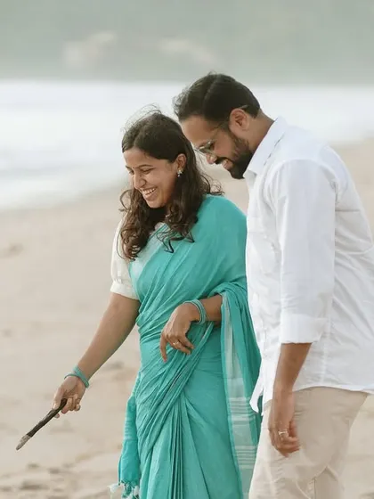 A playful moment captured as the couple examines something they've found on the beach, showcasing their shared curiosity and joy.