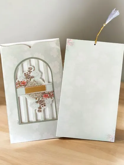 An ethereal wedding invitation featuring delicate die-cuts, soft vellum paper, and a pastel tassel for a touch of whimsy.