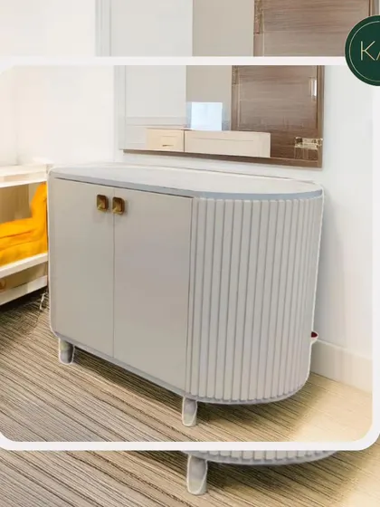 A stylish, curved cabinet with fluted side panels and elegant brass handles. This piece was designed as a chic storage solution for a bedroom or living area.