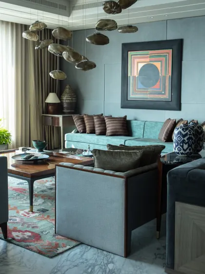 Another angle of the living room, showcasing the layering of textures, patterns, and colors. The design balances bold art pieces with sophisticated furniture and soft furnishings to create a cohesive and inviting atmosphere.