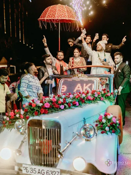 The groom's grand exit in a vintage car, celebrating with his friends.