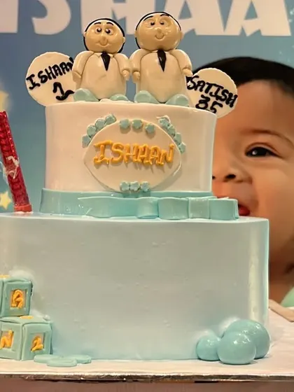 A custom cake designed for a joint birthday celebration. The cake features cute fondant figures representing the birthday boy and his father, adding a unique and personal touch.