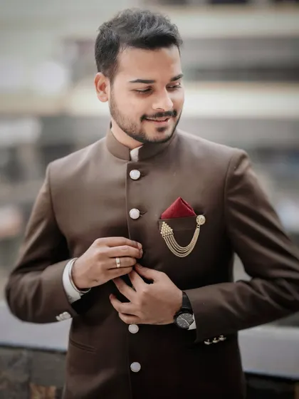 A stylish portrait of the groom adjusting his Jodhpuri suit, showcasing his sharp attire for the engagement ceremony.