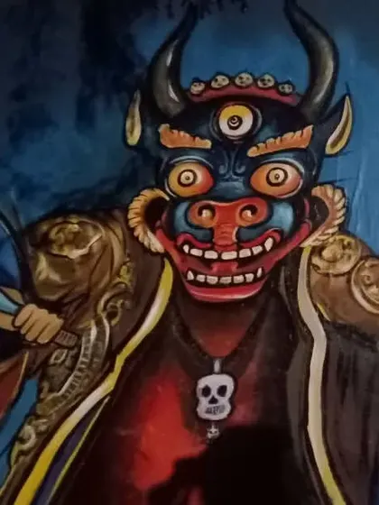 Another view of the three-eyed deity mask, highlighting the detail in the fangs and the skull pendant.
