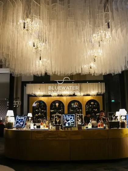 A frontal view of the black and gold bar, showcasing its sleek design and the dramatic lighting from the overhead installation.