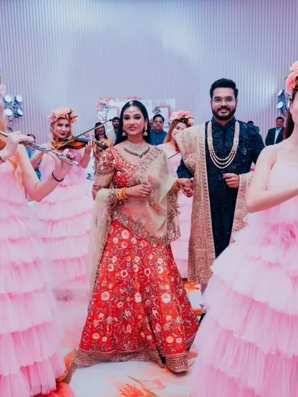 A wide shot of the couple's grand reception entrance, surrounded by a band of female musicians, creating a spectacular visual.