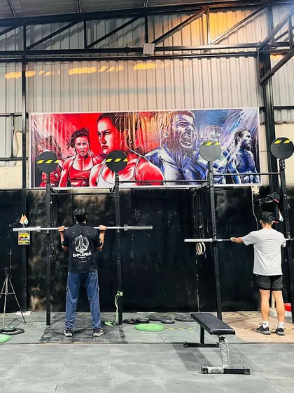Two members getting their back squats in under our inspirational banner. The artwork features fitness icons and sets the tone for hard work and dedication.